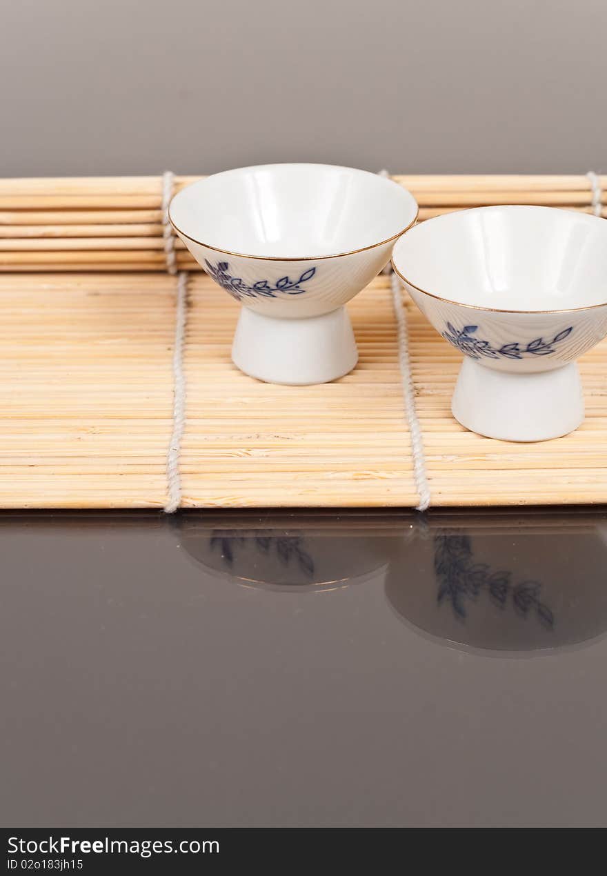 Oriental Alcoholic Sake Cup on a Bamboo Mat. Oriental Alcoholic Sake Cup on a Bamboo Mat