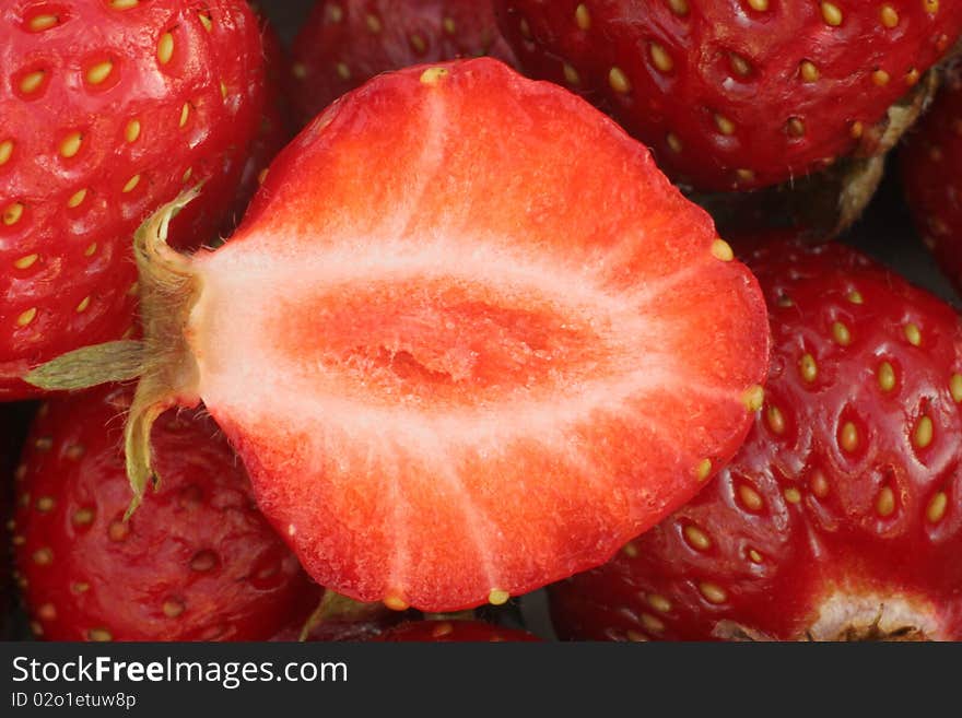 Strawbery slice cut in half with other strawberries in background, macro photograpy. Strawbery slice cut in half with other strawberries in background, macro photograpy.