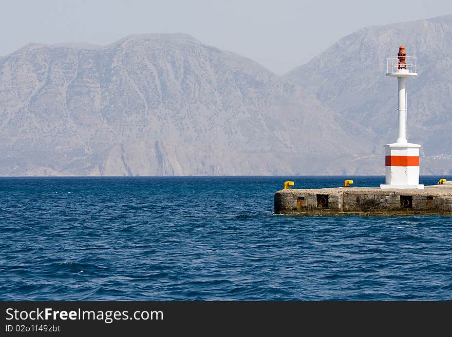 Lighthouse in rocky bay against the mountains