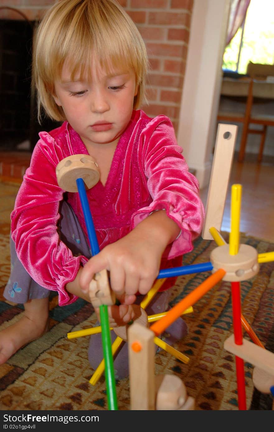 Four year old girl playing withTinker Toys on living room floor. Four year old girl playing withTinker Toys on living room floor