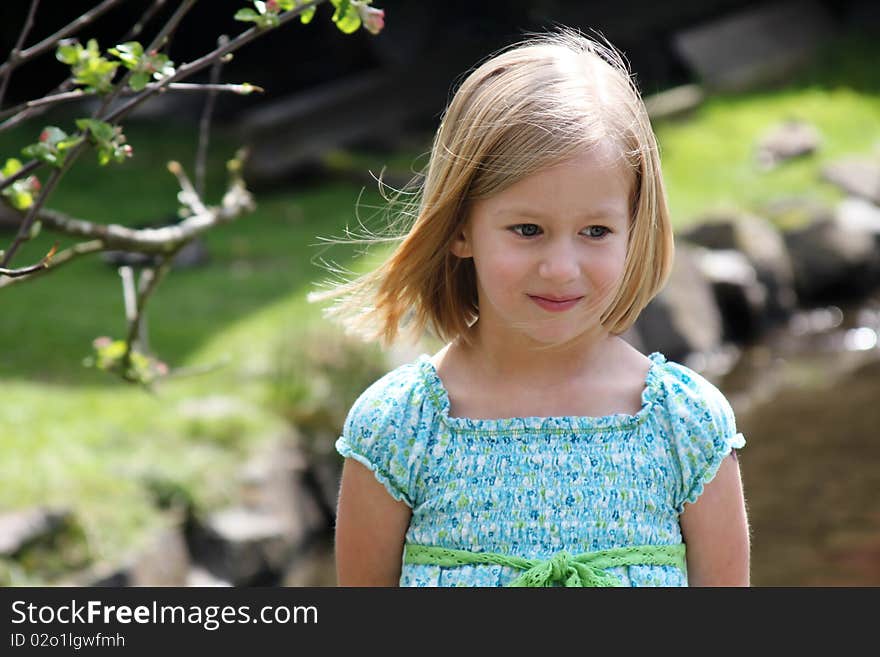 Pretty 5 year old girl in blue dress with light breeze in her hair. Pretty 5 year old girl in blue dress with light breeze in her hair