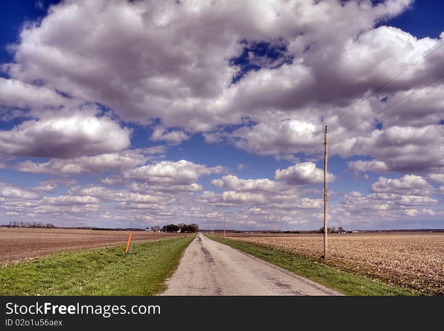 Bare fields and road under clouds