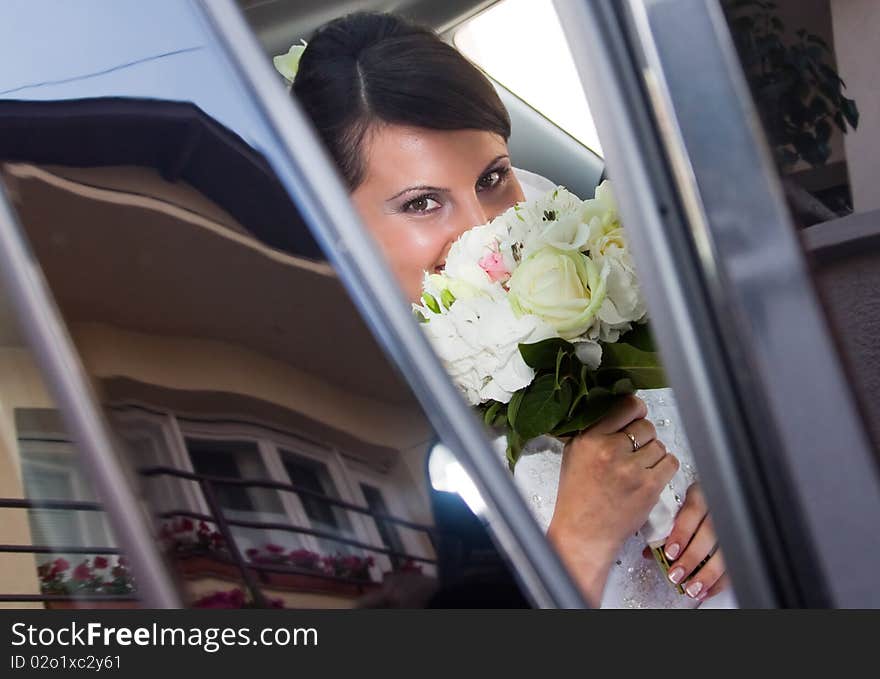 Happy bride with bouquet inside car