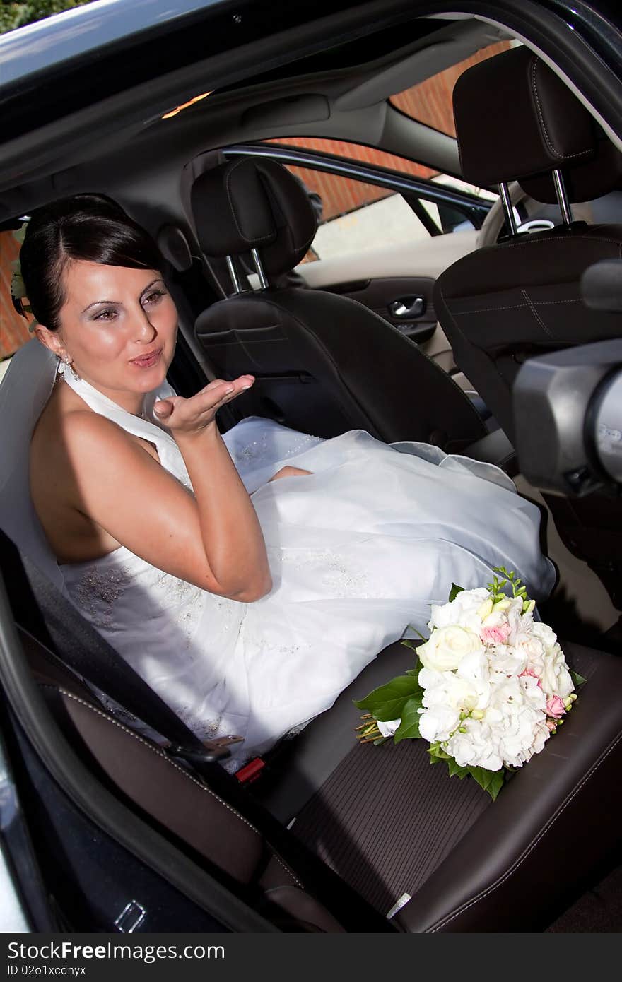 Happy bride with bouquet inside car