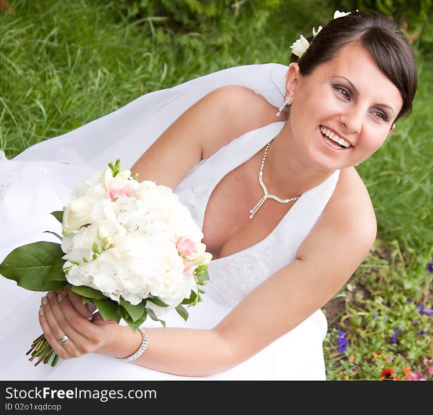 Happy bride with bouquet posing outdoors