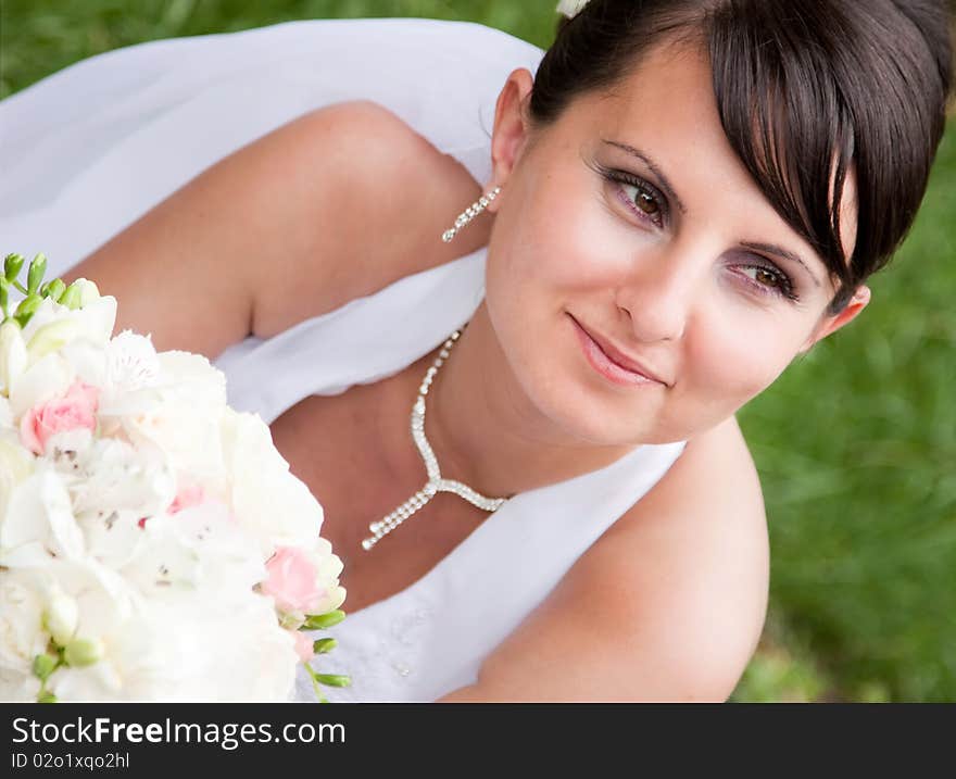 Happy bride with bouquet posing outdoors