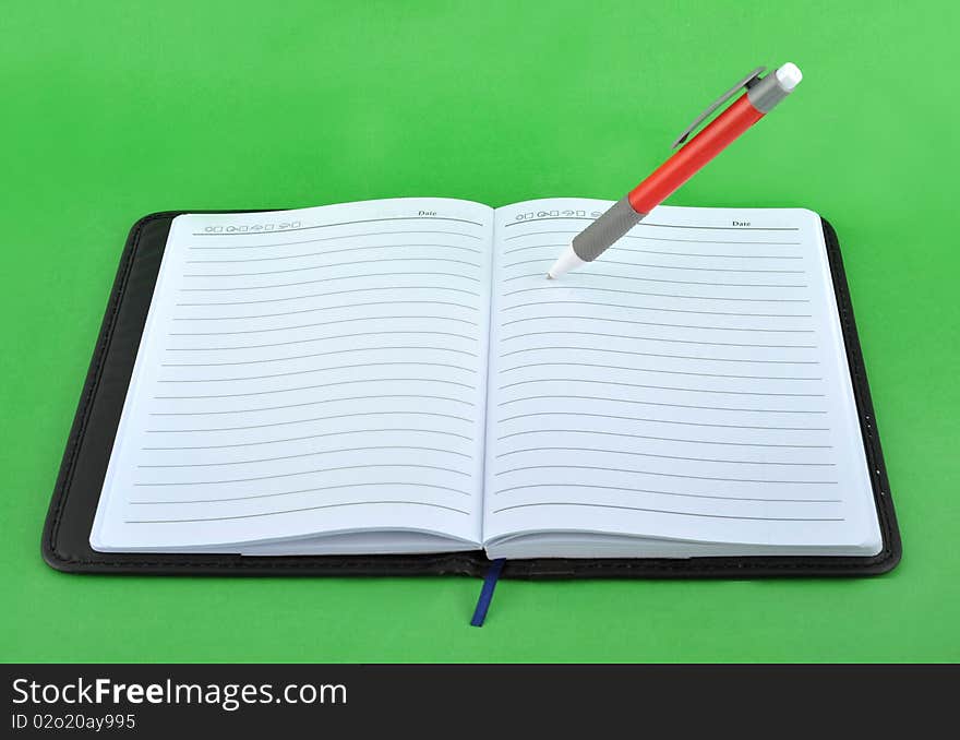 Notebook and pen in the green background