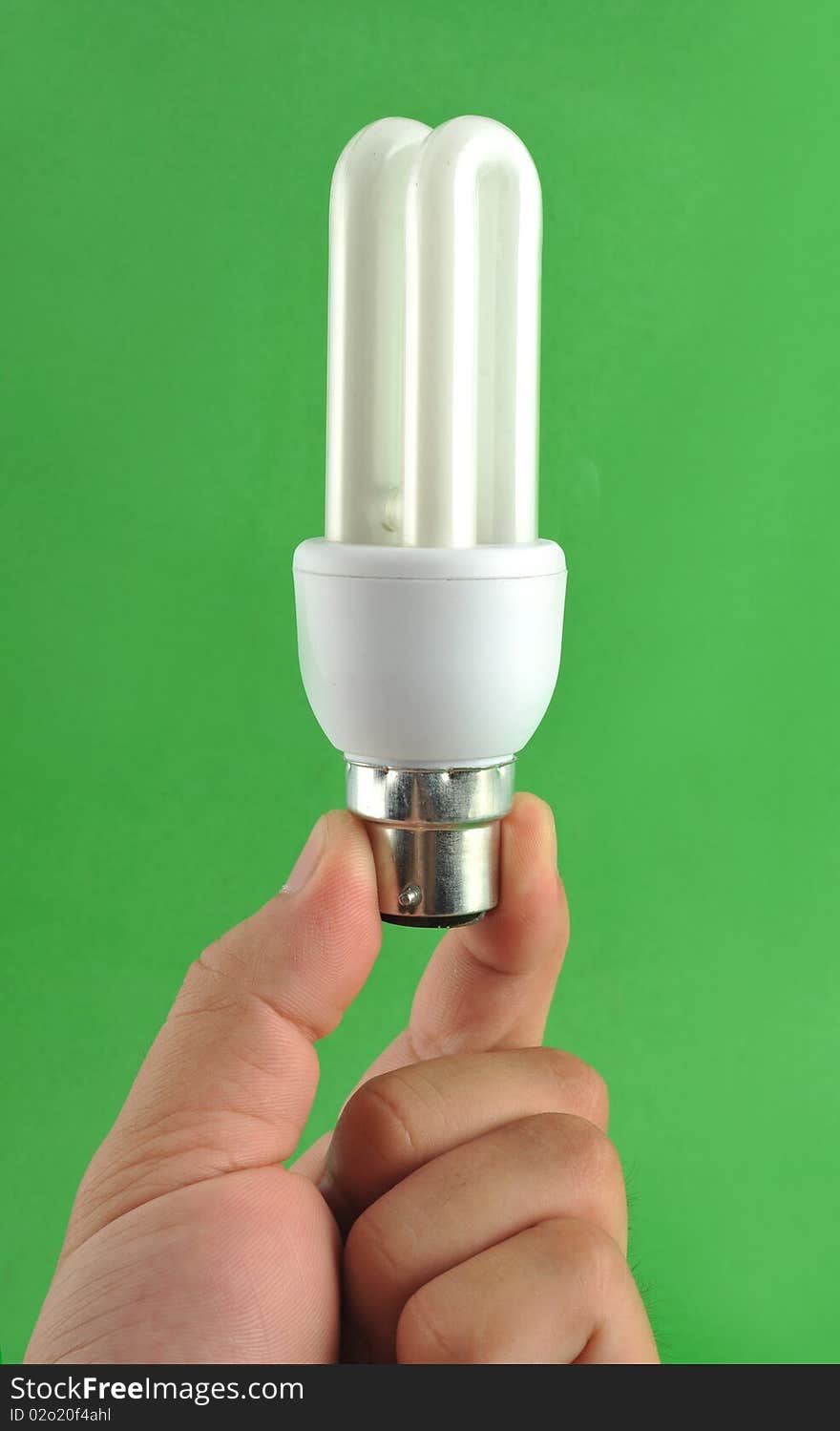 Hand holding energy saving lamp isolated on green background