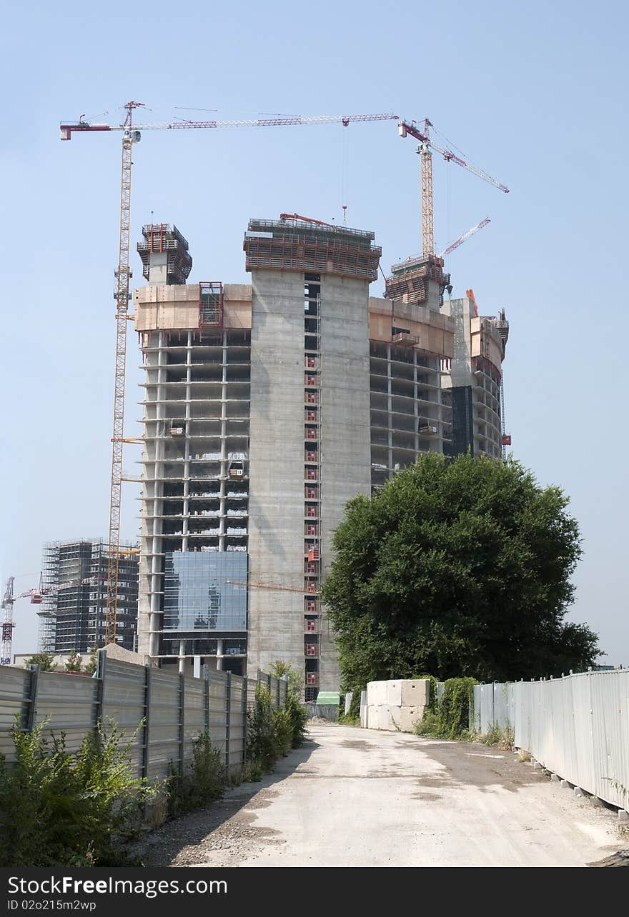 Construction site in Milan (Italy) for the construction of a skyscraper, with many cranes at work. Construction site in Milan (Italy) for the construction of a skyscraper, with many cranes at work.