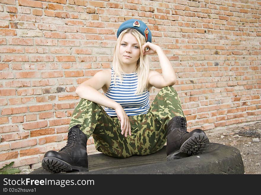 The woman in the military form sits on the tyre and the head is propped up by a hand. The woman in the military form sits on the tyre and the head is propped up by a hand