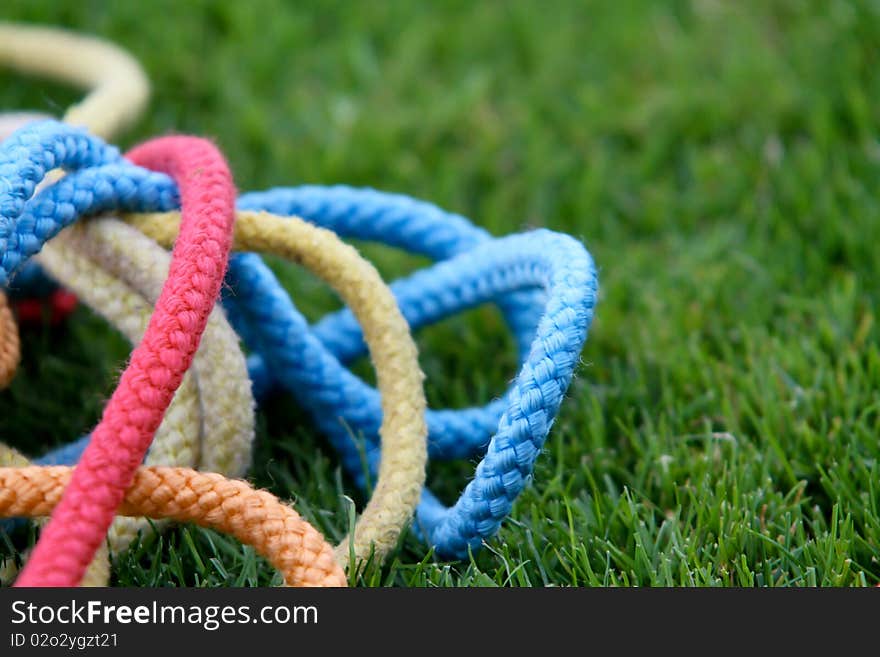 Colorful gymnastics ropes lying in grass. Colorful gymnastics ropes lying in grass