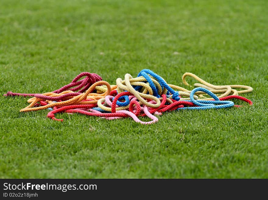 Colorful gymnastics ropes lying in grass. Colorful gymnastics ropes lying in grass