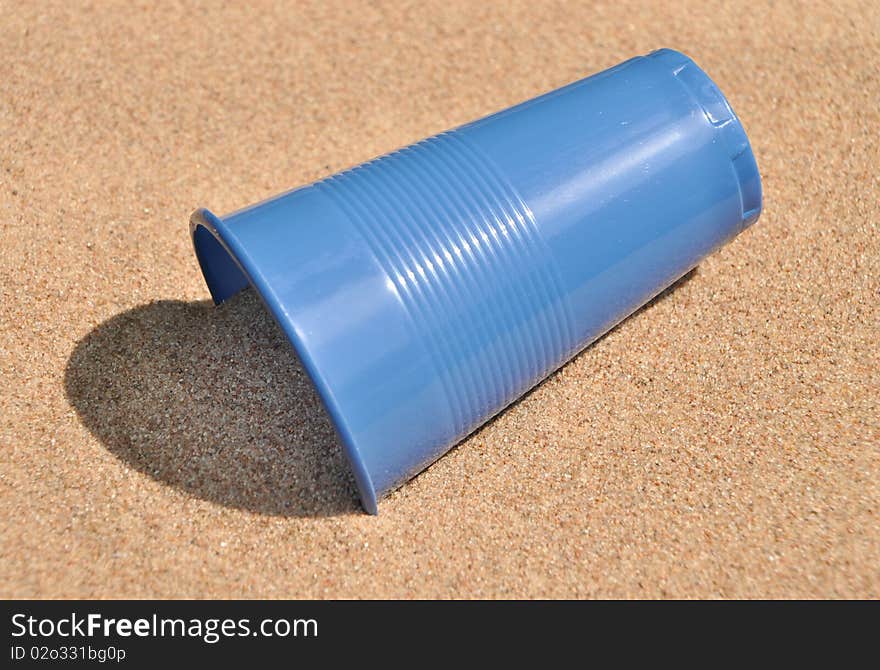 Plastic blue glass on sand. Plastic blue glass on sand.