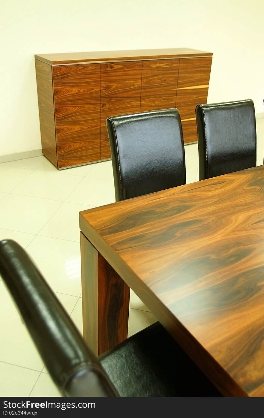 Wooden table and leather black chairs and a wooden locker in background