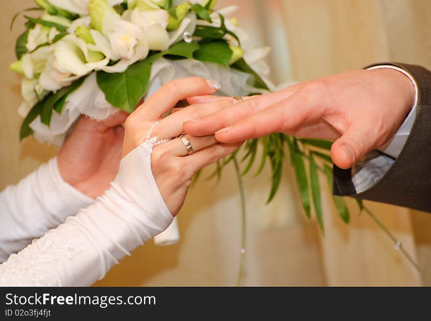 Closeup of a bride putting on the wedding ring on her groom's finger