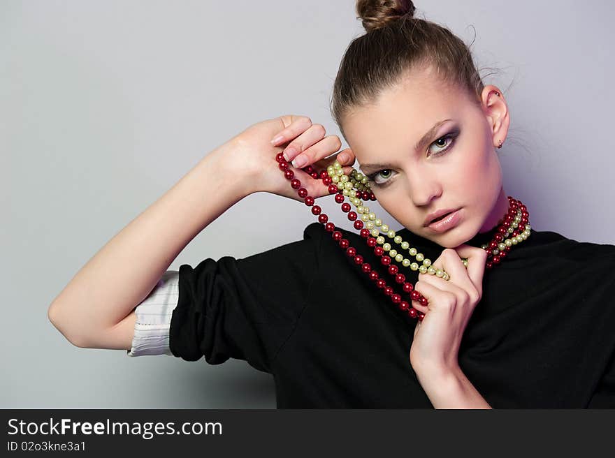 Graceful girl with gray background keeps the beads