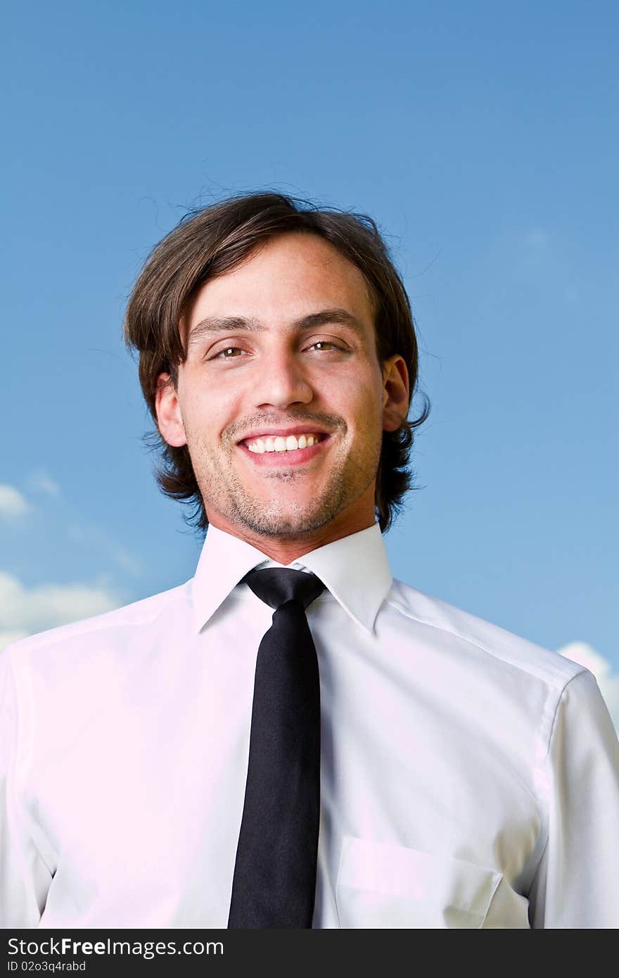 Young businessman with longer hair over a blue sky outside. Young businessman with longer hair over a blue sky outside.