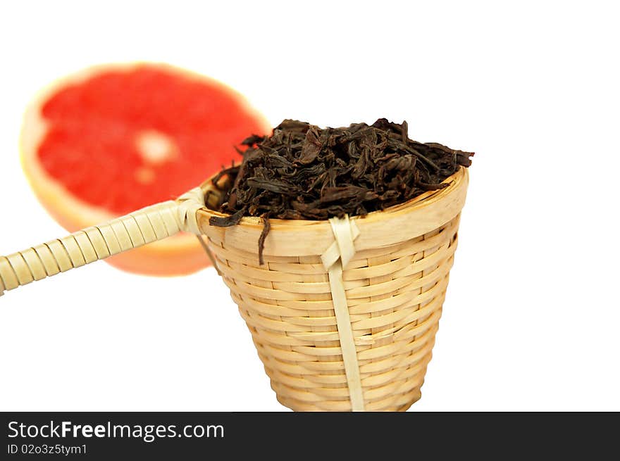 Loose black tea in a wattled basket with a grapefruit isolated  on white background