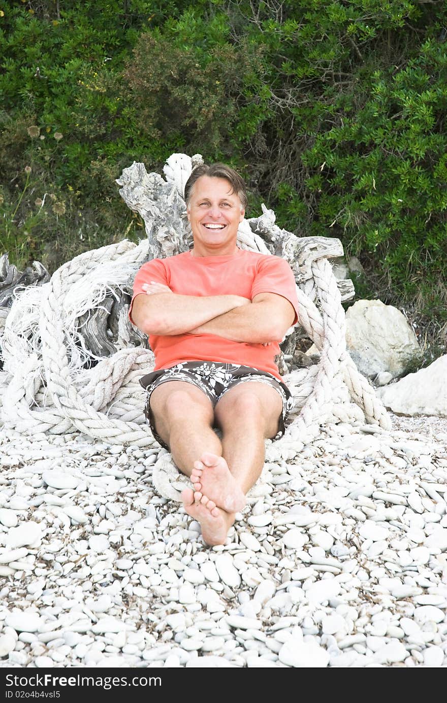 Color portrait photo of a happy forties man sitting on a rocky beach in Greece. Color portrait photo of a happy forties man sitting on a rocky beach in Greece