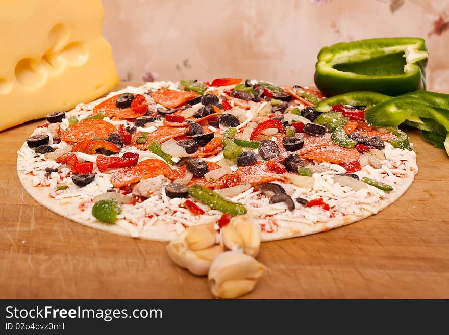 Raw pizza with vegetables and pepperoni