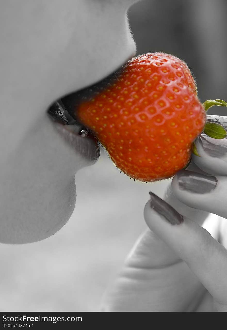 Macro shot of a women biteing into a  large strawberry. Macro shot of a women biteing into a  large strawberry