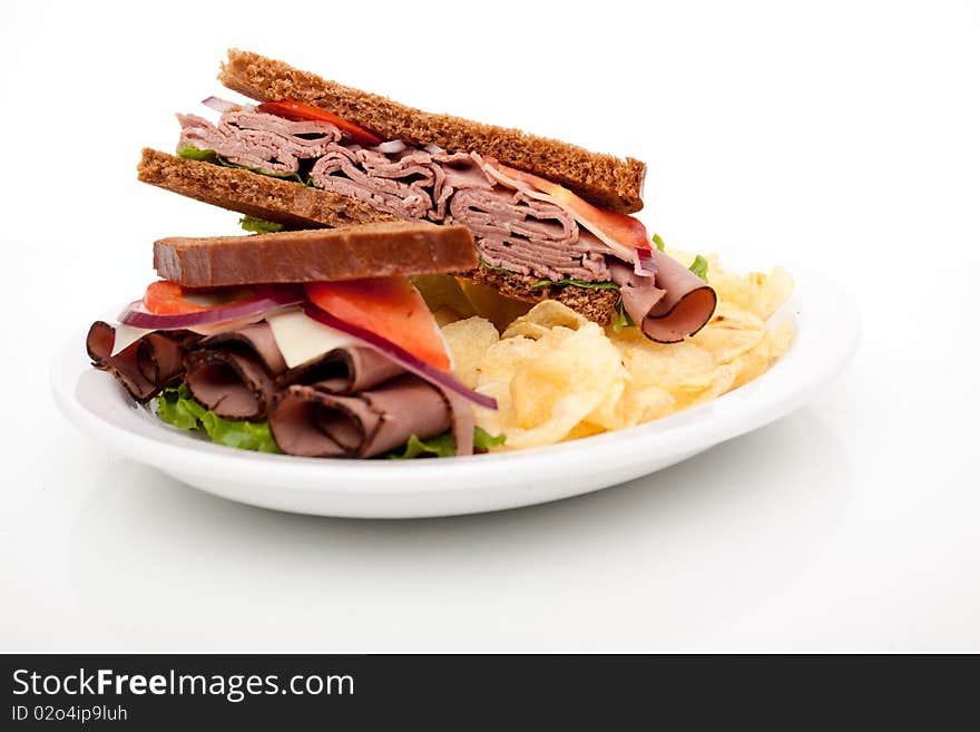 Delicious roast beef sandwich platter with whole wheat bread and potato chips. Delicious roast beef sandwich platter with whole wheat bread and potato chips