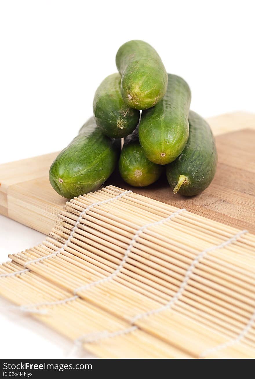 Pyramid of cucumbers on top of a cutting board with a bamboo mat. Pyramid of cucumbers on top of a cutting board with a bamboo mat