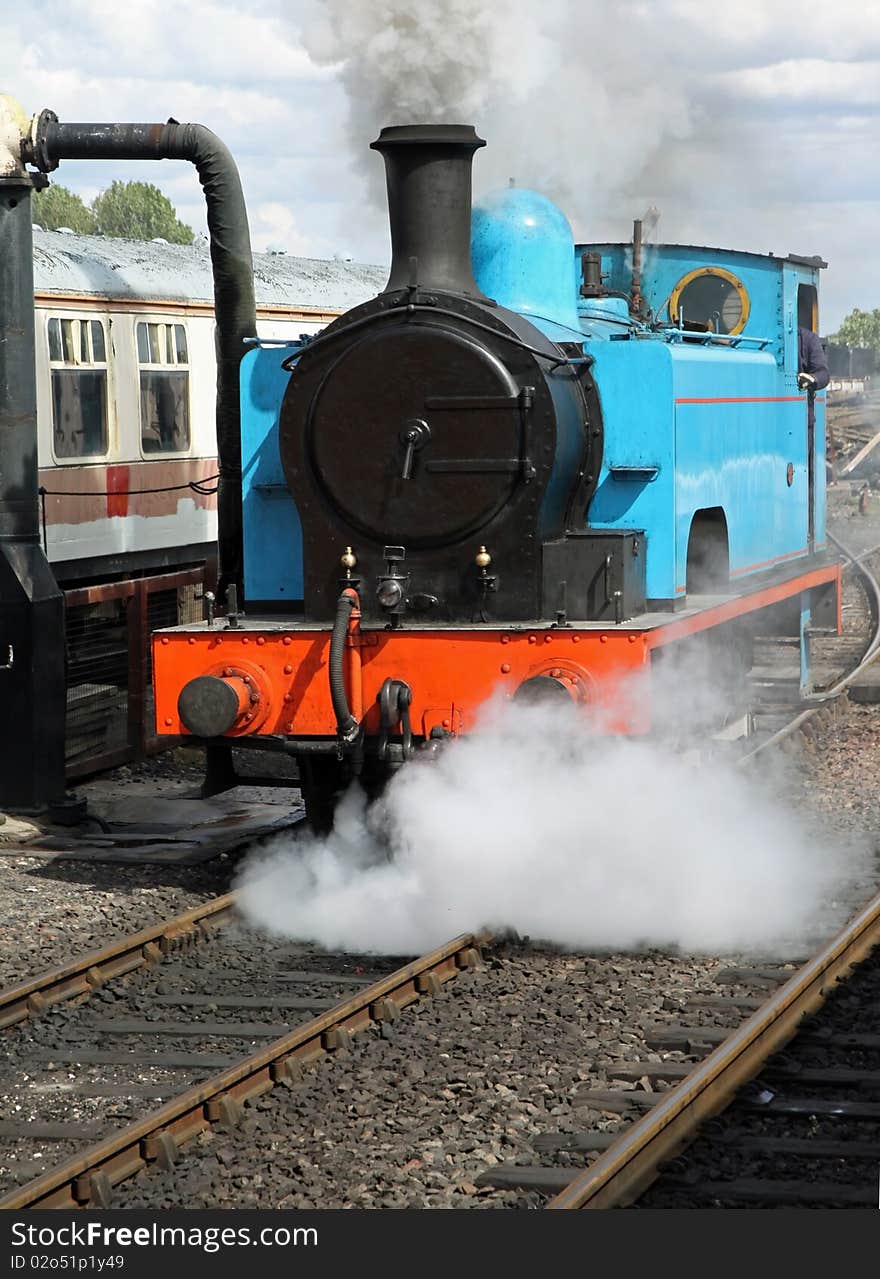 Stream train in yard waiting to take on coal with steam venting from the loco. Stream train in yard waiting to take on coal with steam venting from the loco