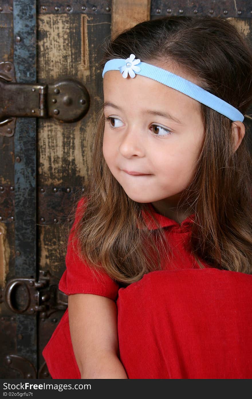 Cute brunette girl sitting against an antique trunk wearing a headband. Cute brunette girl sitting against an antique trunk wearing a headband