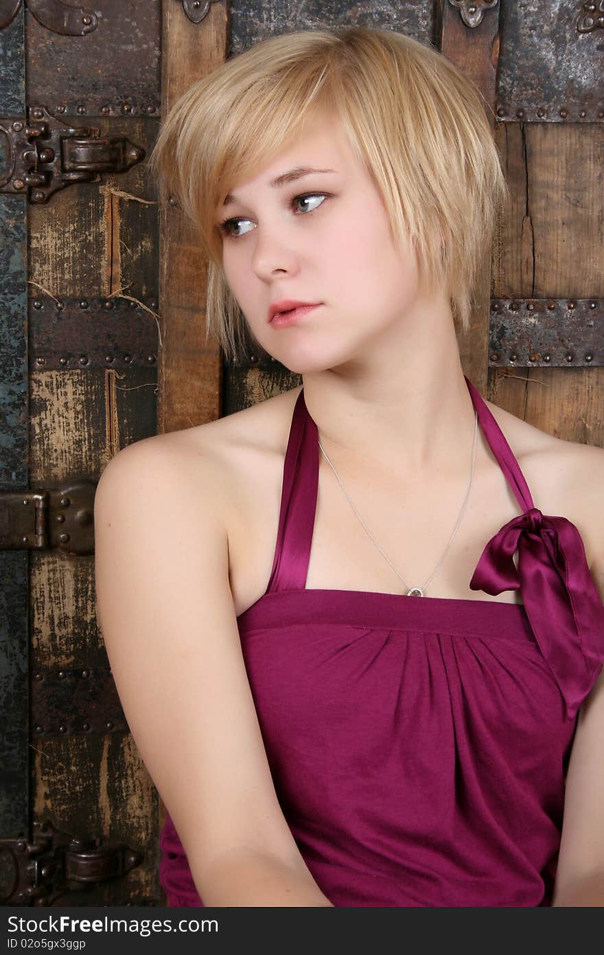 Beautiful blond sitting against an antique trunk with a serious expression. Beautiful blond sitting against an antique trunk with a serious expression