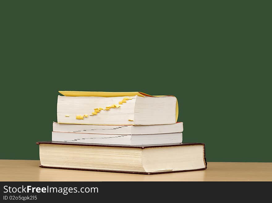 Stack of books with apple & green chalkboard