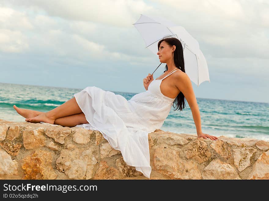 Coastline sitting woman with umbrella