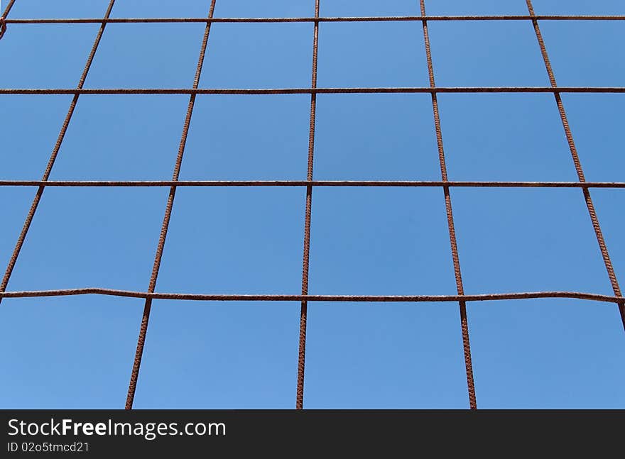 Converging view of rusty lattice on blue sky background