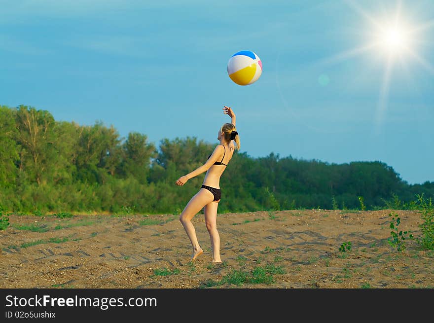 Young girl playing with a ball on the sandy beach