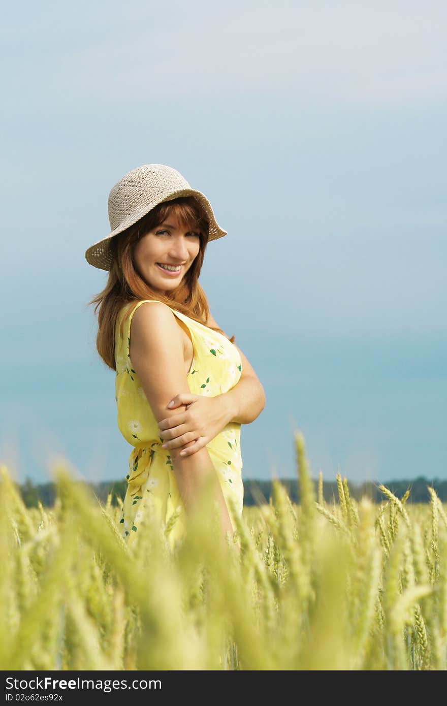 Model in hat smiling in field. Model in hat smiling in field