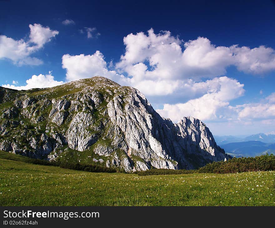 Rock with blue sky and clouds and  meadow with fowers. Rock with blue sky and clouds and  meadow with fowers