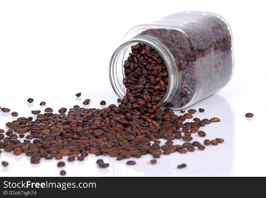 Coffee beans inside glass jar drop on white background. Coffee beans inside glass jar drop on white background