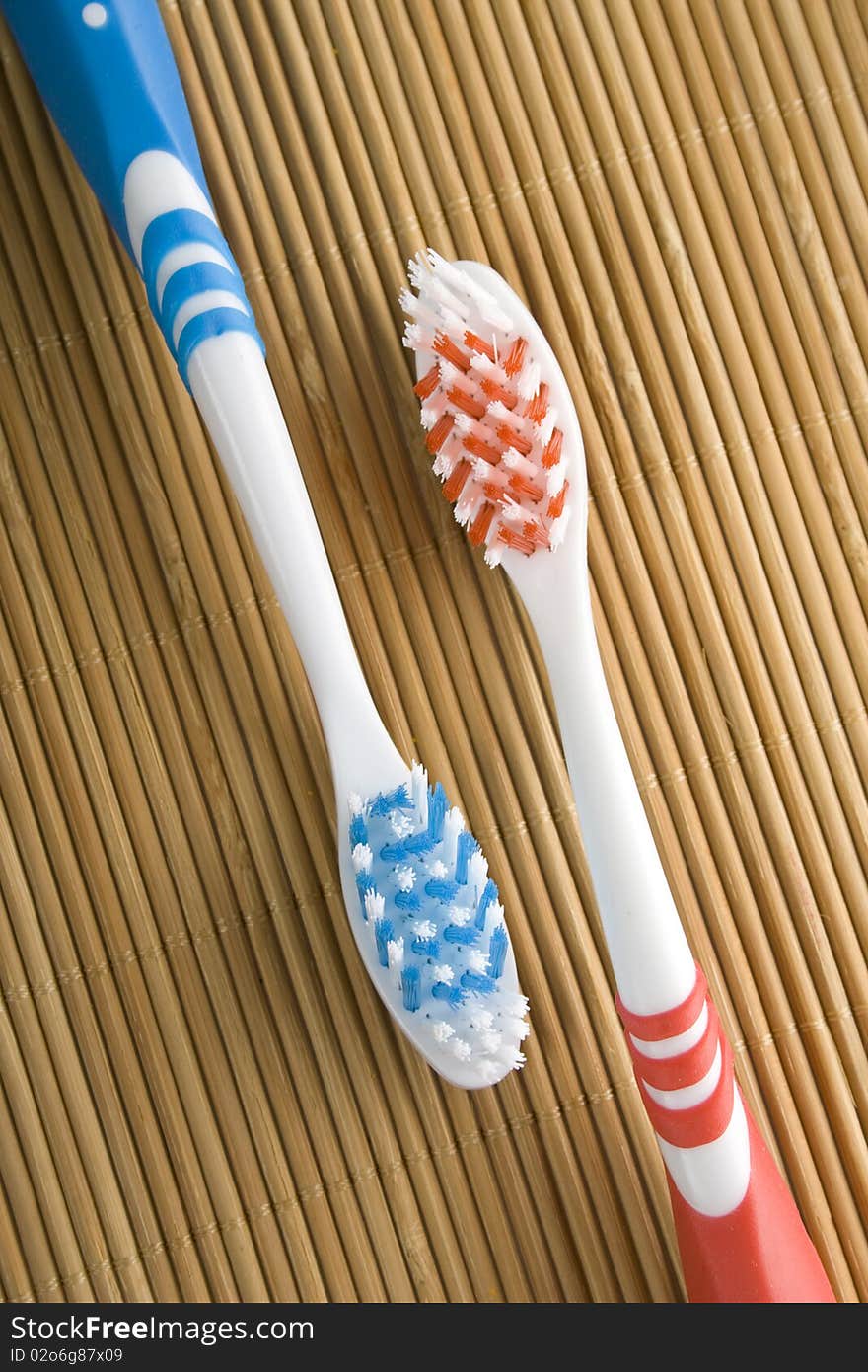 Red and blue toothbrushes lying on a wooden surface