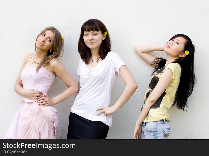 Three female friends standing in front of a white wall