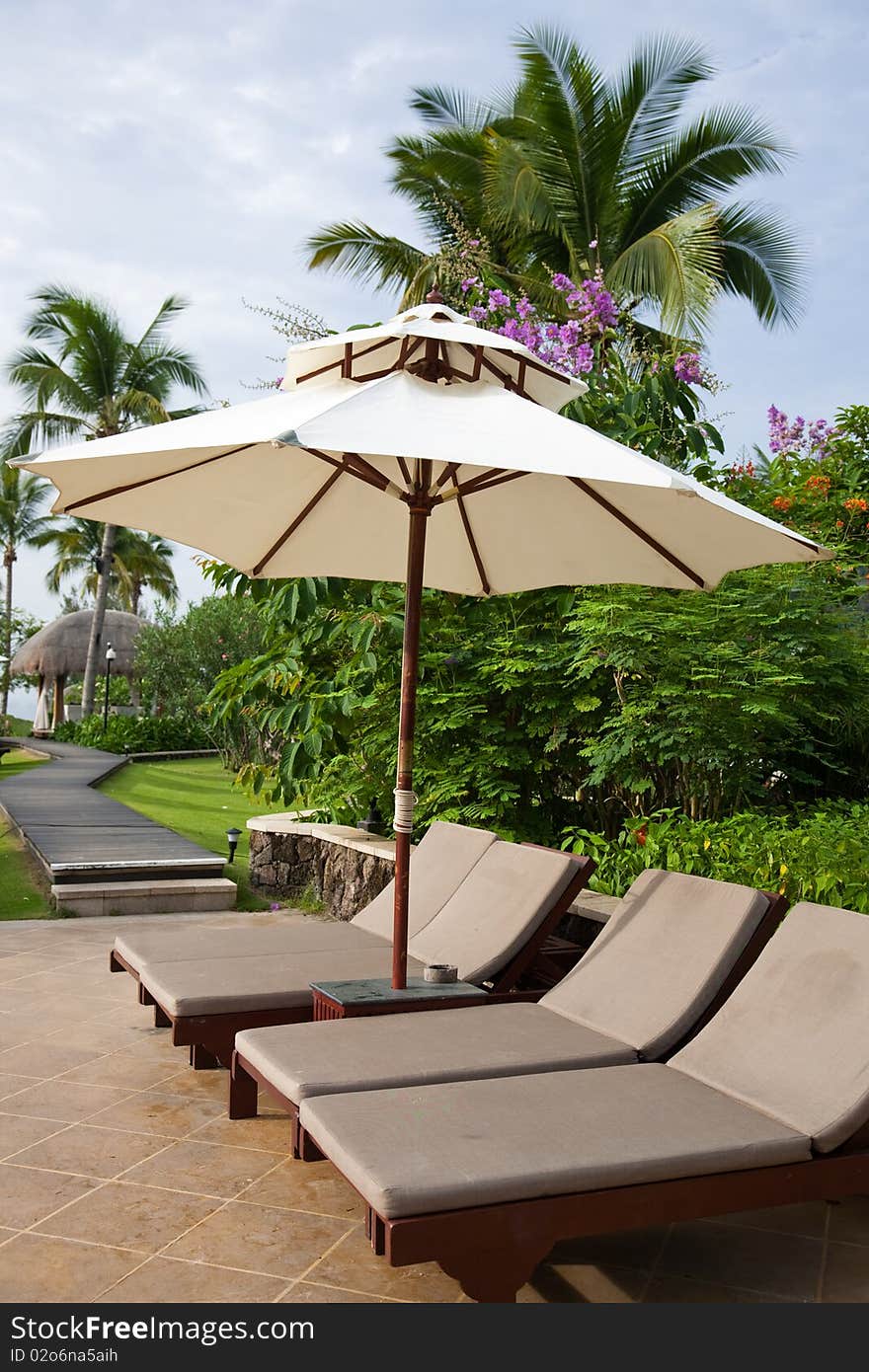 Sunshade and chaise longue in tropical resort.