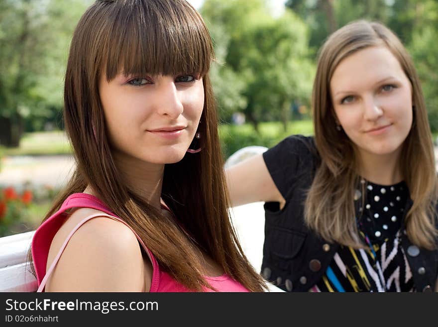 Two female friends sitting on bench