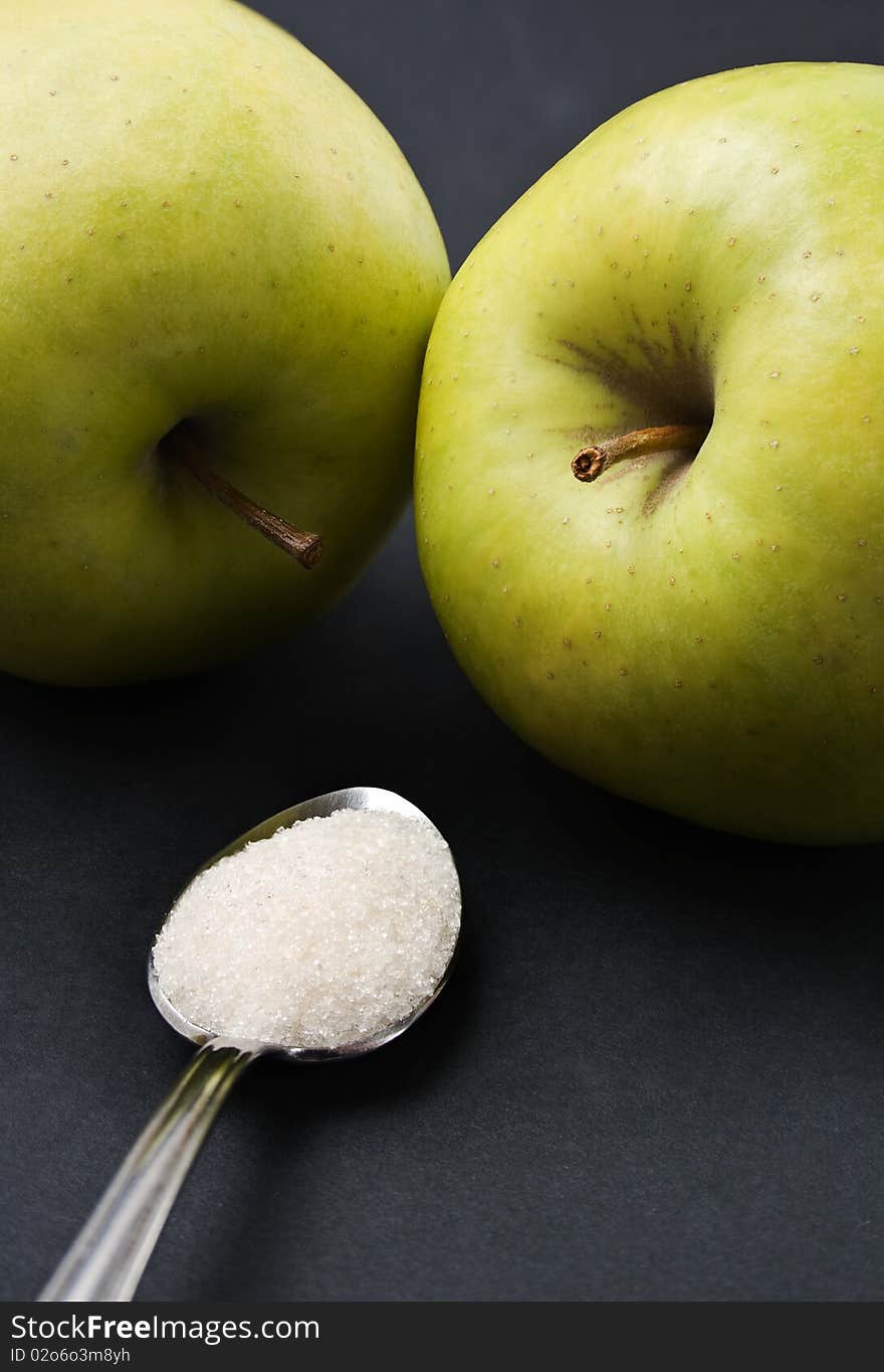 Teaspoon full of white sugar versus two green apples. Teaspoon full of white sugar versus two green apples