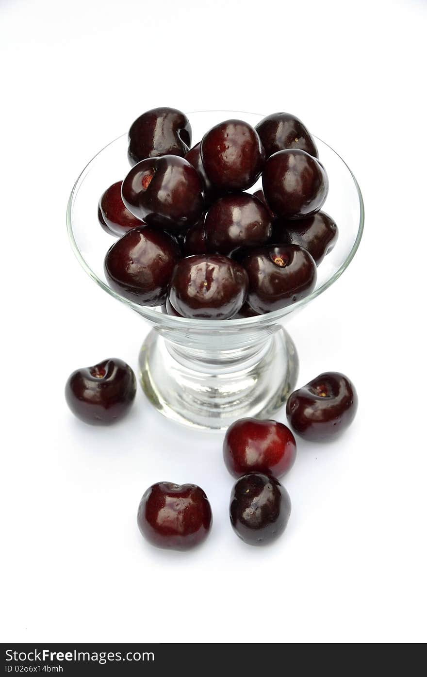 View of cherries in glass dessert bowl over white. View of cherries in glass dessert bowl over white