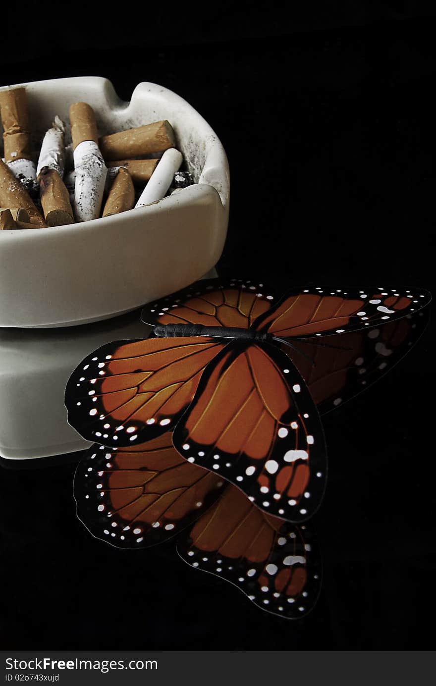 Ashtray with cigarette on a reflecting surface of a glass table in a cafe. Ashtray with cigarette on a reflecting surface of a glass table in a cafe