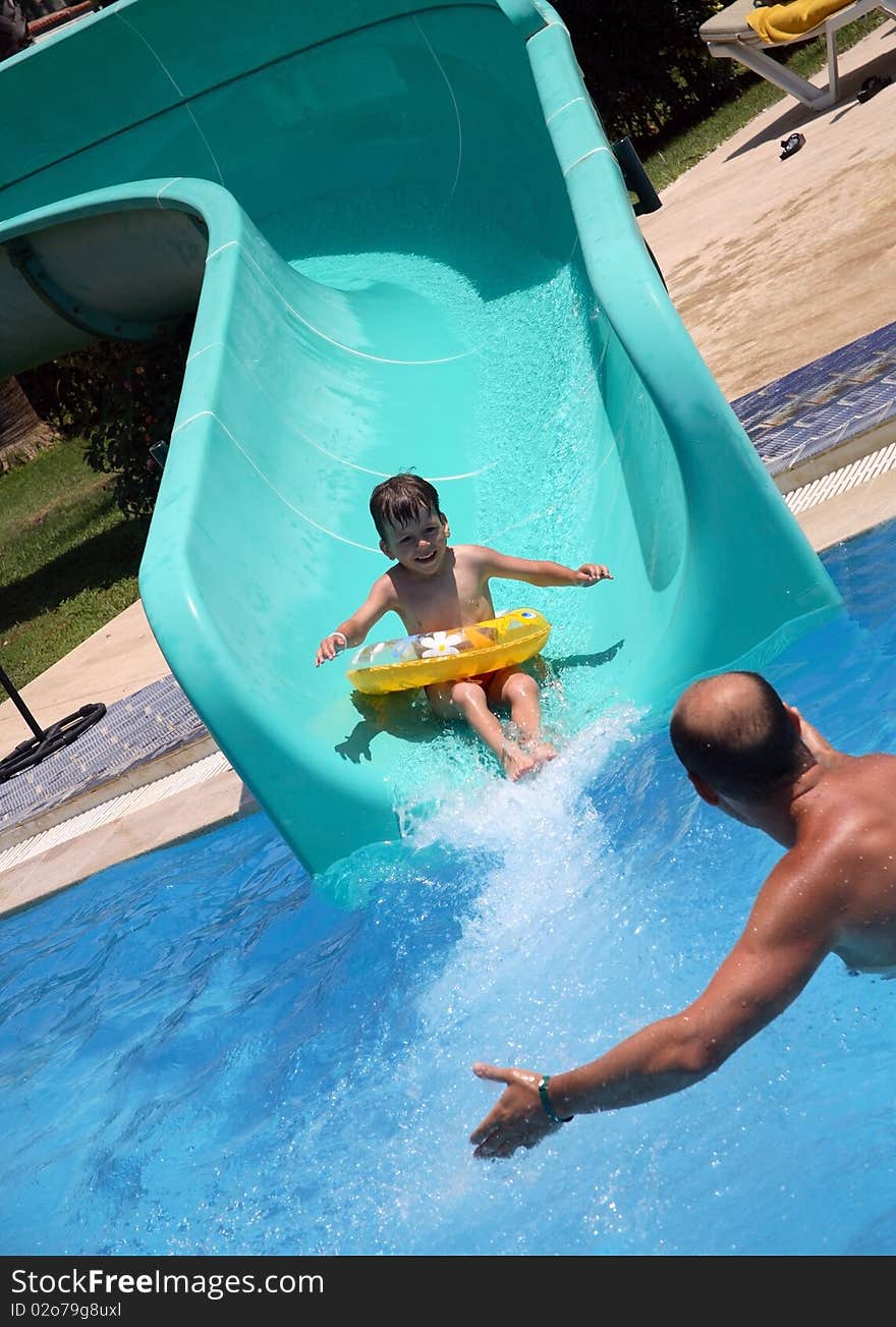 Father catches child on water slide, happy boy