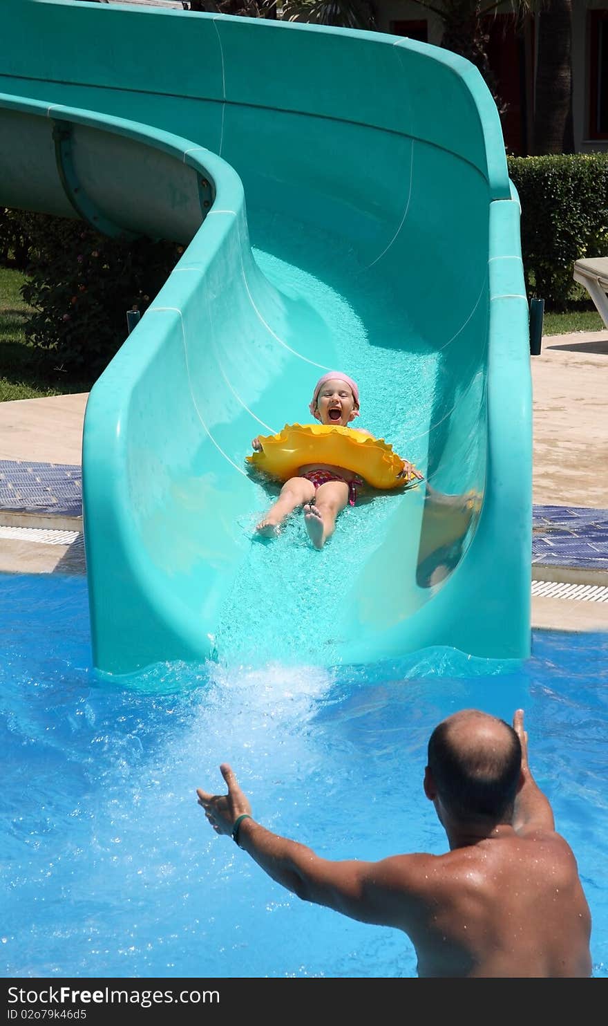 Father catches child on water slide, action