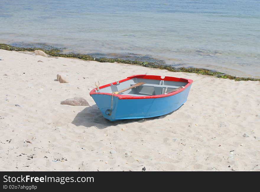 Blue and red rowing boat on a sandy beach. Blue and red rowing boat on a sandy beach