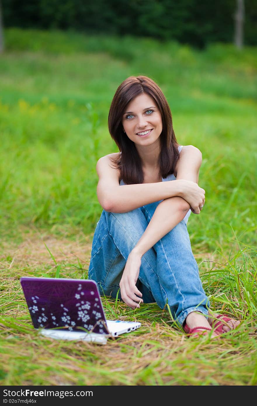 Brunette student girl in the park with notebook on grass