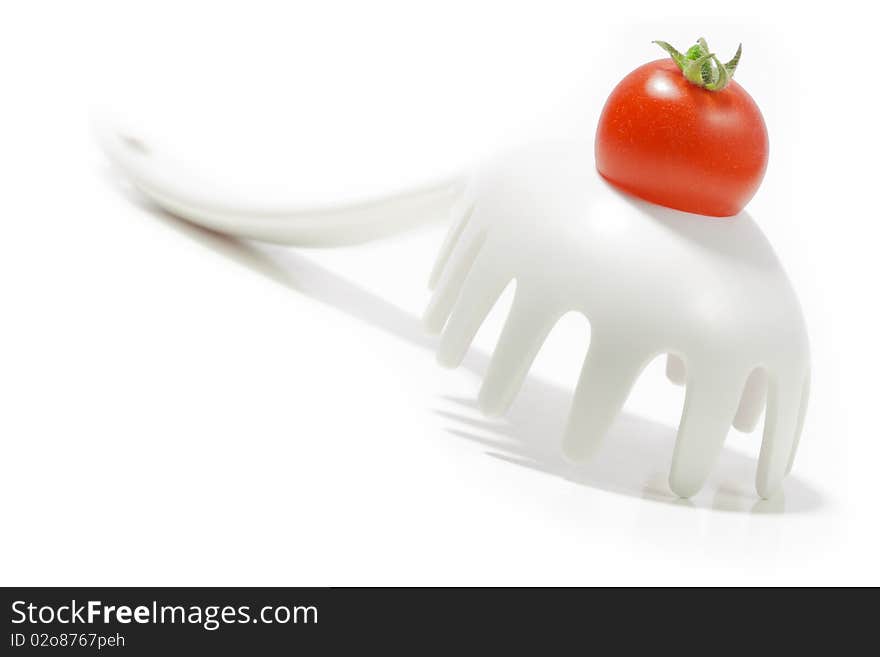 Ripe cherry tomato on a pasta ladle/fork. Isolated on white background.