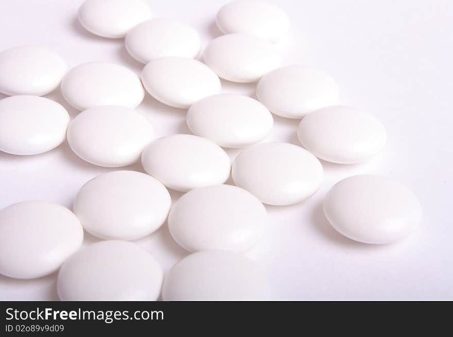 Some white tablets on white background (close up). Some white tablets on white background (close up)